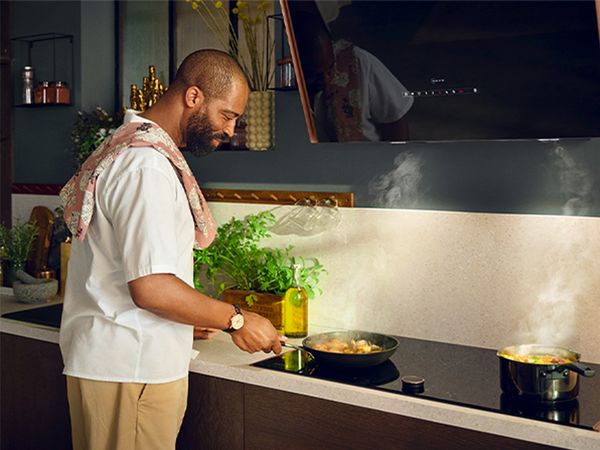 Person cooking on induction hob with hood above