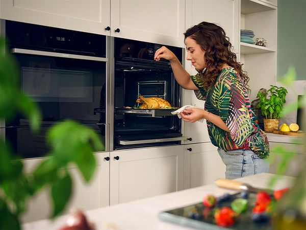 Person seasoning chicken in oven