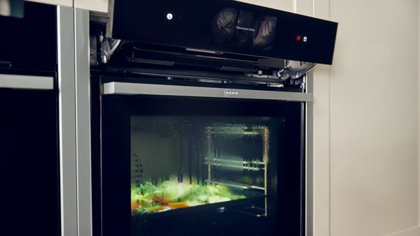 През конденза по вратата на фурната се виждат зеленчуци, от които се вдига пара