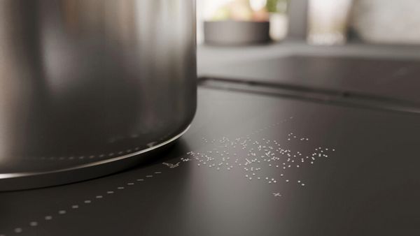 Zoutkorrels liggen naast een pan op de matzwarte kookplaat