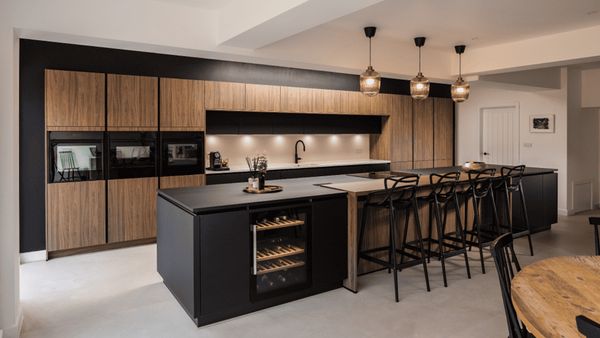 Dark wood open plan kitchen with multiple NEFF appliances