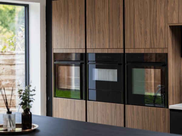Side by side built in appliances in dark wooden cabinets