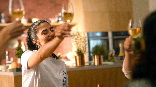 Group of friends toasting wine glasses in kitchen