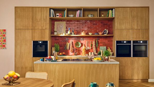 A kitchen featuring wooden cabinets and a red brick wall, creating a warm and inviting atmosphere.  