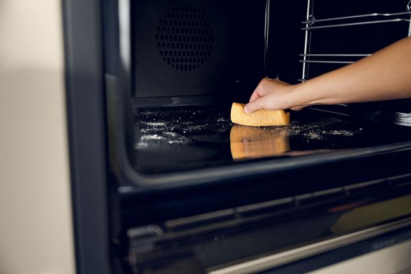 Cleaning the interior of a NEFF oven with a sponge.