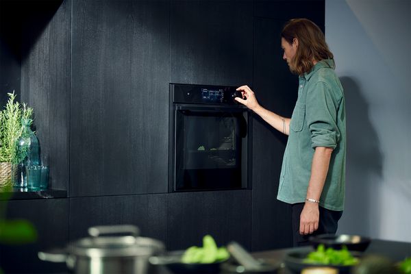 A woman stands in front of an oven, preparing to cook or check on a dish inside. 