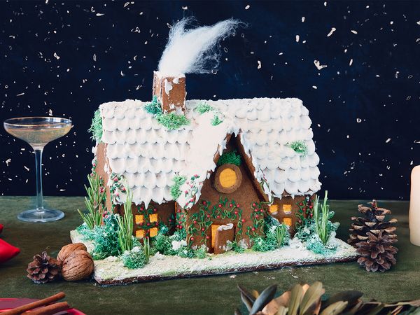 Празнична коледна къщичка от меденки, украсена с глазура и празнични поръски.