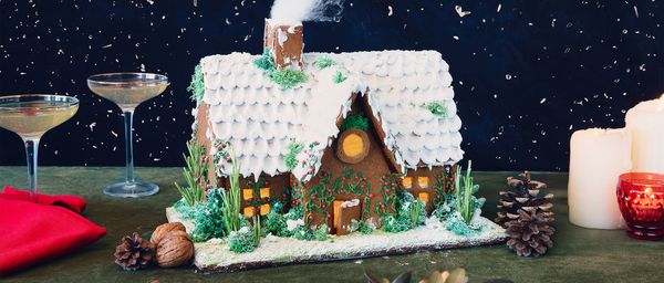 Festive Christmas gingerbread house decorated with icing and festive sprinkles.