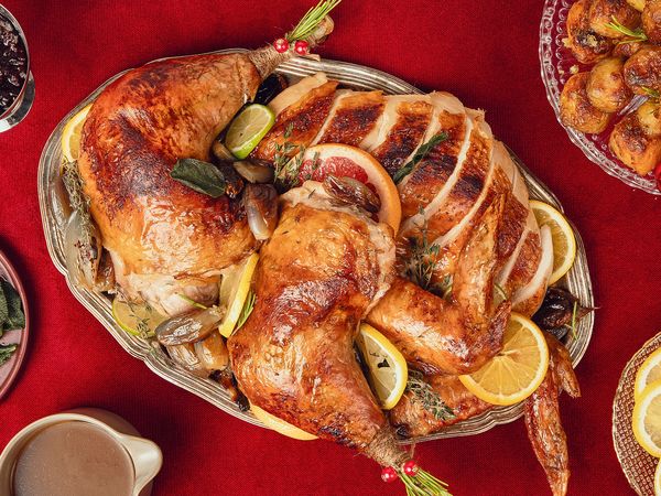 Carved up lemon and thyme roast turkey with golden skin on a serving platter in a festive christmas setting.
