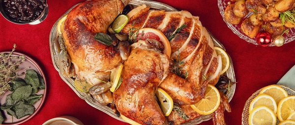 Carved up lemon and thyme roast turkey with golden skin on a serving platter in a festive christmas setting.