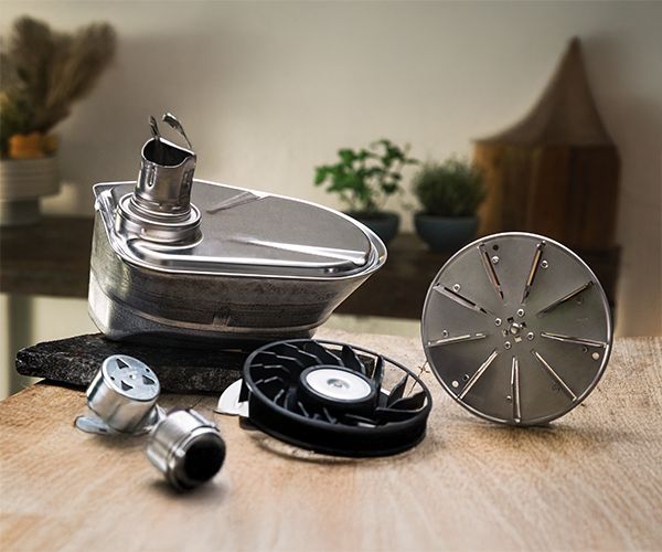 
       Eine Sammlung von Edelstahlteilen f&uuml;r K&uuml;chenger&auml;te, darunter eine Sch&uuml;ssel, ein Scheibenaufsatz und ein L&uuml;fterblatt, kunstvoll auf einem Tisch pr&auml;sentiert.
      