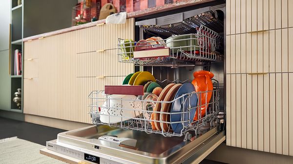 Moderni astianpesukone, joka on täynnä värikkäitä lautasia ja kulhoja.
