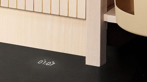 Пералня, пълна с цветно пране, поставена в светъл дървен шкаф до две кошници за съхранение.