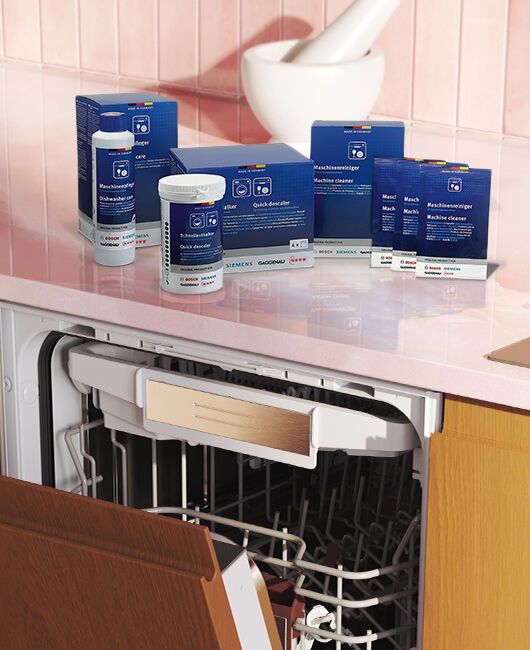 Lavastoviglie aperta con prodotti Cleaning&Care Neff disposti sul piano di lavoro della cucina