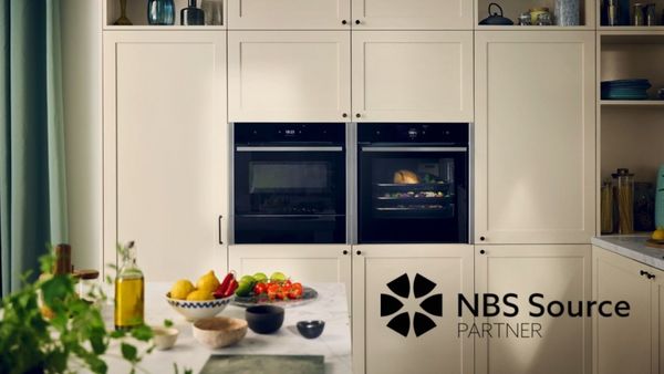 Decorated light kitchen with multiple NEFF appliances and NBS Source Partner logo overlay
