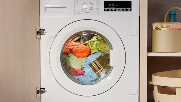 A man is installing a washing machine in a modern kitchen, preparing for laundry tasks in a convenient space. 
