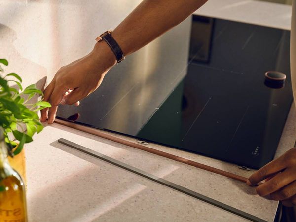 Person customising the coloured trim on a countertoop hob