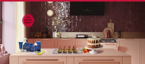Auf einer K&uuml;cheninsel stehen verschiedene Reinigungsprodukte neben einer verspielten Anordnung dekorativer Osterhasen. Ein Banner mit der Aufschrift &bdquo;20 % Oster-Rabatt&ldquo; ist ebenfalls zu sehen.