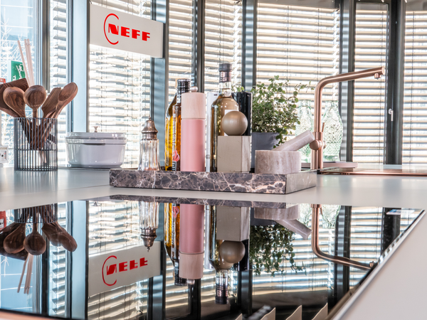 Detailansicht einer modernen NEFF K&uuml;che mit Induktionskochfeld, Arbeitsfl&auml;che und K&uuml;chenaccessoires im Showroom M&uuml;nchen.