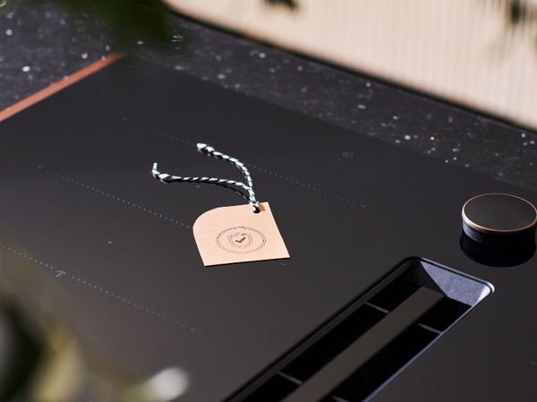 Eine Person &ouml;ffnet einen eleganten, modernen Ofen und enth&uuml;llt Gl&auml;ser mit Zutaten, vor einem stilvollen schwarzen K&uuml;chendekor.