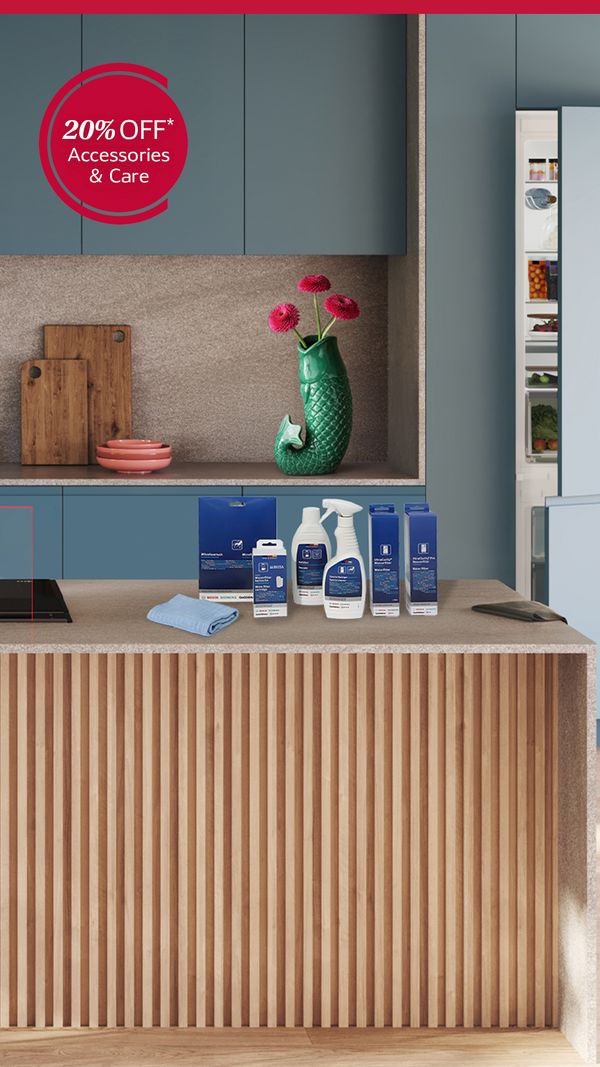 Contemporary blue kitchen with a wood-slatted island, two stools and cooktop with plated food and cleaning and care products and a 20% off accessories and care badge.