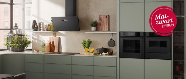 Kookplaat met afzuiging in matte afwerking met pan aardappelen op een marmeren werkblad. 