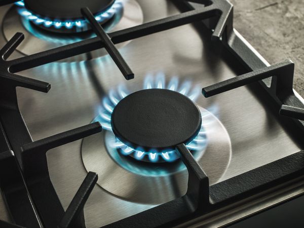 Close-up of a gas cooktop with blue flames, illustrating the power and efficiency of traditional cooking methods. 
