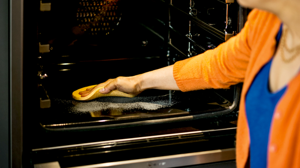 Frau wischt Pyrolyse R&uuml;ckst&auml;nde aus einem NEFF Backofen