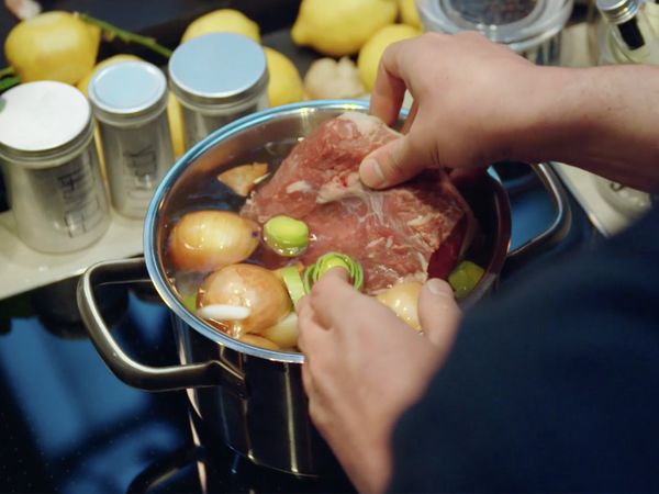 Person placing food in a cooking pot