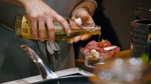 Man pouring oil on raw meat