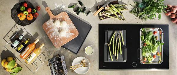 Vogelperspektive einer Küchenzone mit frischem Gemüse, Saucen, Kochutensilien und gegrilltem Spargel.