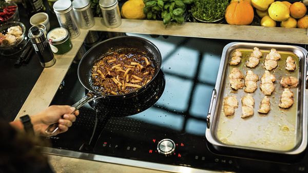 Person using Power Move on NEFF Induction Hob to cook in different zones