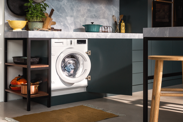 Cucina con lavatrice da incasso piena di bucato