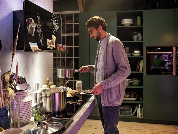 Man cooking in kitchen with NEFF appliances