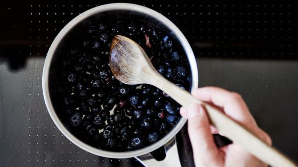 Person stirring blueberries in pan