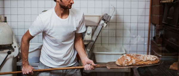 Man putting loaf of bread into oven