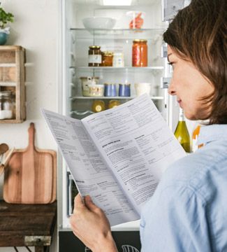 Donna che consulta il libretto di istruzioni del frigorifero