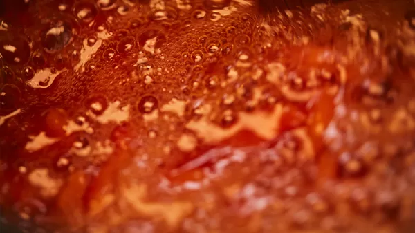 Close-up of hands chopping fresh tomatoes on a wooden cutting board with a sharp knife, creating a finely diced mixture.