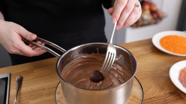 Dipping truffle balls into melted milk chocolate