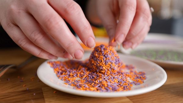 Rolling truffle ball in orange and purple sprinkles