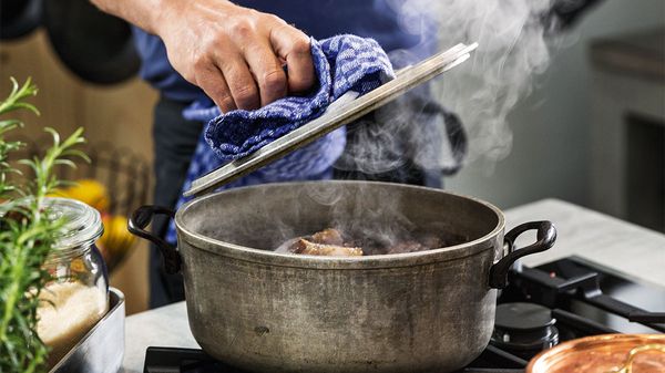 Person lifting lid from cooking pot to check food on NEFF Gas Hob