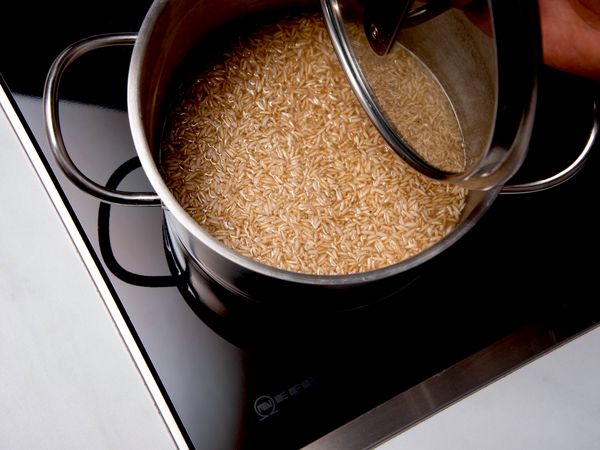 Pentola con riso integrale in cottura su piano a induzione NEFF, con coperchio sollevato