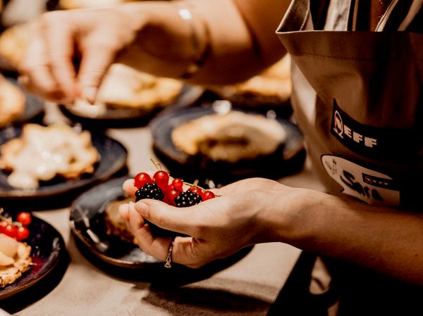 Person putting berries on pastry during NEFF event