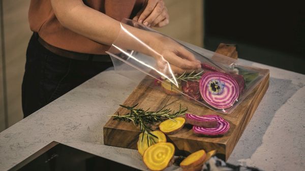 Woman adding vegetables to vaccum sealed bag for NEFF SousVide drawer